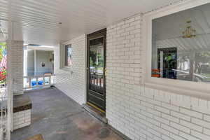 Entrance to property with brick siding and a porch
