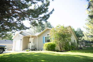 Ranch-style house featuring a garage, a front lawn, and driveway