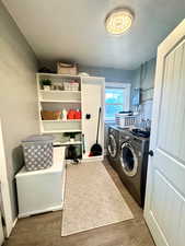 Laundry room with independent washer and dryer, wood finished floors, and electric panel