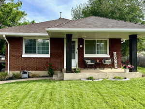 View of front facade with brick, a porch, and a front yard