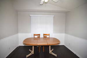 Dining room featuring wainscoting, wood finished floors, lofted ceiling, and a ceiling fan