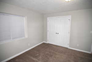 Bedroom #5 with carpet floors, a textured ceiling, a closet, and baseboards