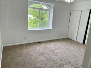 Unfurnished bedroom featuring light carpet, a closet, baseboards, and a ceiling fan