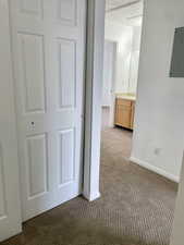 Corridor featuring carpet flooring, electric panel, and baseboards