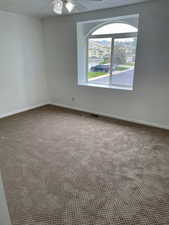 Empty room with carpet floors, a ceiling fan, and baseboards