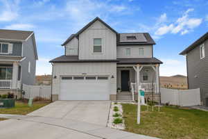 View of front of house with board and batten siding, a porch, solar panels, an attached garage, and driveway