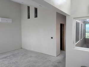 Empty room with a wall mounted air conditioner and concrete floors