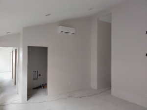 Corridor featuring an AC wall unit and lofted ceiling