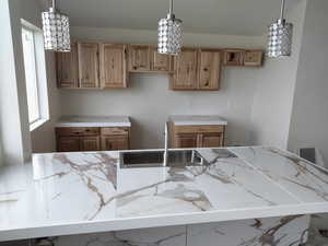 Kitchen featuring a sink, hanging light fixtures, and light stone countertops