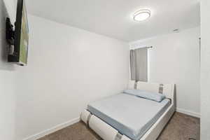Bedroom featuring carpet flooring, baseboards, and a textured ceiling