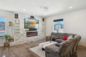 Living room featuring a stone fireplace, wood finished floors, recessed lighting, and baseboards