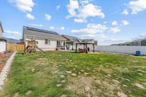 Back of house with a playground, a gazebo, a patio, stucco siding, and roof mounted solar panels