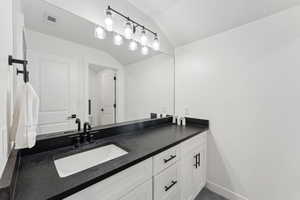 Bathroom featuring vaulted ceiling, vanity, and baseboards