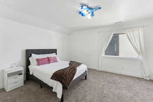 Bedroom with carpet, a textured ceiling, vaulted ceiling, and baseboards