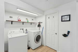 Laundry area with independent washer and dryer and light wood finished floors