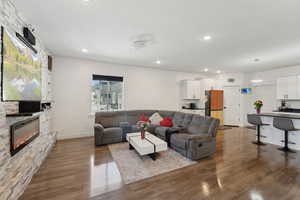 Living area featuring dark wood-type flooring, a stone fireplace, recessed lighting, plenty of natural light, and baseboards