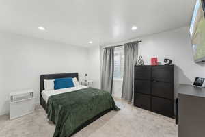 Bedroom with light colored carpet and recessed lighting