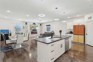 Kitchen featuring a sink, freestanding refrigerator, dark countertops, stainless steel dishwasher, and plenty of natural light