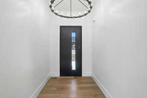 Entrance foyer with wood finished floors and a chandelier