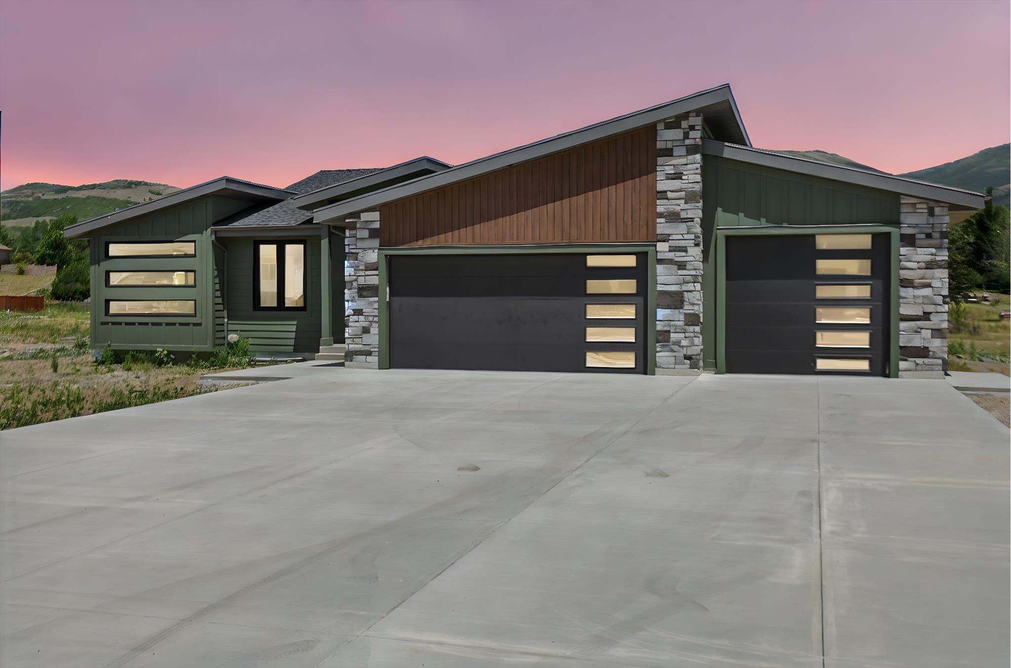 Contemporary home featuring stone siding, a garage, driveway, and a mountain view