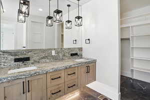 Bathroom with marble finish flooring, double vanity, recessed lighting, a walk in closet, and decorative backsplash