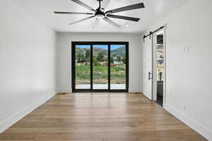 Spare room featuring a barn door, a mountain view, light wood-type flooring, a ceiling fan, and recessed lighting