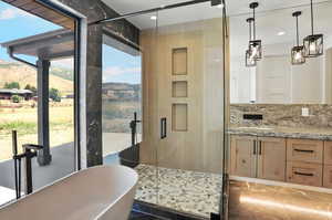 Kitchen with light stone countertops, pendant lighting, recessed lighting, and light brown cabinets