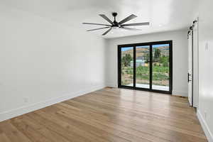 Spare room featuring a barn door, ceiling fan, light wood-style flooring, and recessed lighting