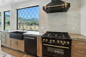 Kitchen featuring black appliances, wall chimney range hood, backsplash, and light wood-style flooring
