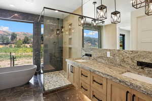 Full bathroom featuring a chandelier, marble tiled floors, a shower stall, a soaking tub, and double vanity