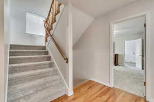 Staircase with wood finished floors and baseboards