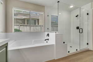 Bathroom featuring a bath, a shower stall, wood finished floors, vanity, and recessed lighting