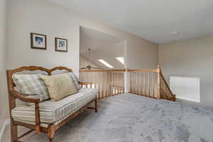 Sitting room with carpet, ceiling fan, a skylight, and an upstairs landing