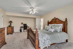 Bedroom with light colored carpet, baseboards, ceiling fan, and an office area