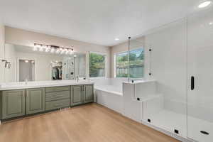 Bathroom with a shower stall, a bath, double vanity, wood finished floors, and a walk in closet