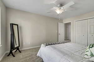 Carpeted bedroom with baseboards, a ceiling fan, and a closet