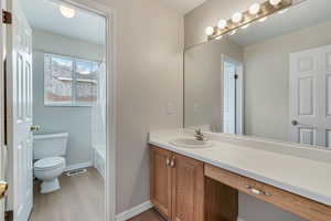 Full bathroom featuring vanity, toilet, wood finished floors, and baseboards