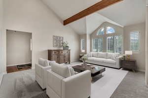 Carpeted living room featuring baseboards, beam ceiling, and high vaulted ceiling