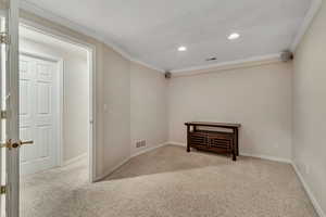 Empty room with carpet flooring, ornamental molding, recessed lighting, and baseboards