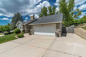 View of front of property featuring stone siding, concrete driveway, a gate, an attached garage, and stucco siding