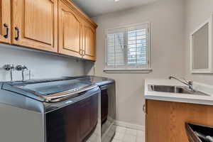 Washroom with cabinet space, washer and clothes dryer, light tile patterned floors, and baseboards