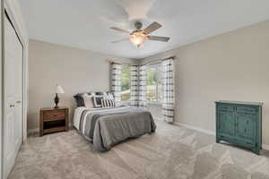 Bedroom with light colored carpet, baseboards, a ceiling fan, and a closet