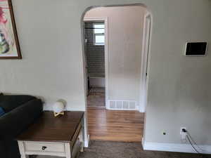 Hallway with arched walkways, baseboards, and carpet flooring