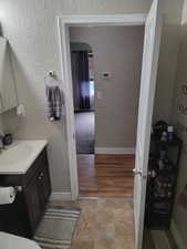 Bathroom with vanity, a textured wall, and baseboards