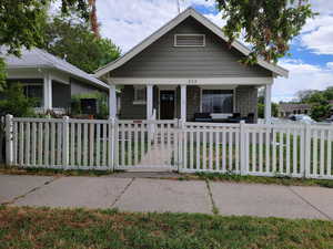 View of front of property with covered porch and a fenced front yard
