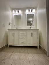 Full bathroom featuring double vanity and baseboards