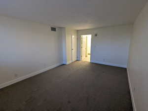 Empty room with baseboards and dark carpet