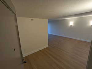 Empty room with wood finished floors, baseboards, and a textured ceiling
