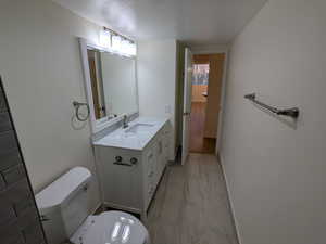 Bathroom with toilet, marble look tile flooring, and vanity