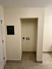 Washroom with hookup for an electric dryer, marble look tiles, hookup for a washing machine, and baseboards